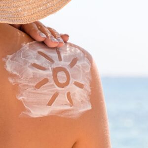 Close-up of a shoulder with a sun drawn in sunscreen, highlighting proper sun protection.