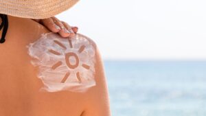 Close-up of a shoulder with a sun drawn in sunscreen, highlighting proper sun protection.
