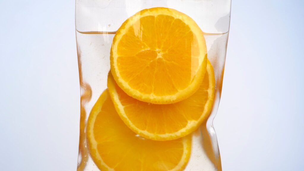 A medical IV bag filled with liquid and slices of fresh oranges, symbolizing High-Dose IV Vitamin C therapy.